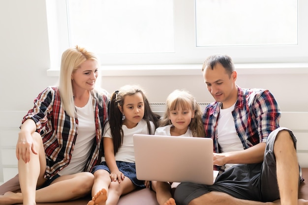 Famille animée achetant en ligne allongée sur le lit à la maison