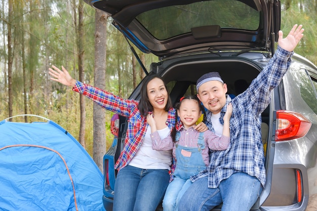 Une famille asiatique assise dans un coffre de voiture va camper en vacances. Voyage en famille en voiture.