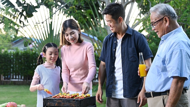 Photo famille asiatique ayant un barbecue à la maison. cuisson du barbecue grillé pour le dîner dans la cour. mode de vie en vacances d'été.