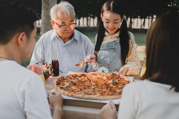 Famille asiatique ayant une pizza dans le jardin à la maison. Parent avec mode de vie enfant et grand-père dans l'arrière-cour.