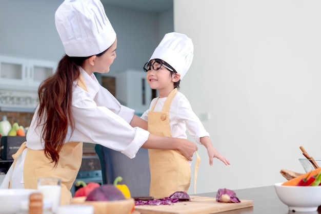Famille asiatique dans la cuisine. Maman enseigne à son fils à cuisiner des aliments sains pendant les vacances d'été.