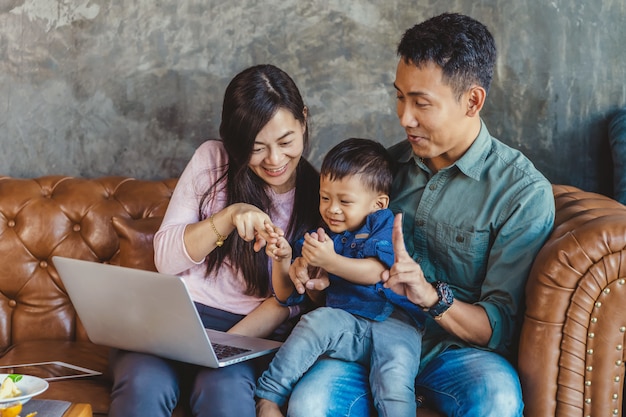 Famille asiatique avec fils cherche le dessin animé via ordinateur portable de technologie et jouer ensemble