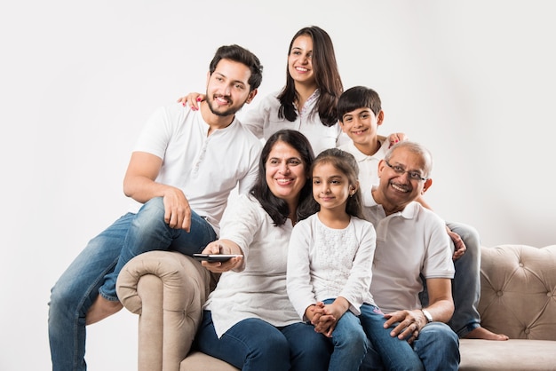 Famille asiatique indienne de plusieurs générations regardant la télévision à la maison tout en étant assis sur un canapé ou un canapé, vue latérale, mise au point sélective