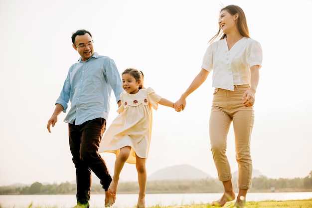 Famille asiatique marchant et se tenant la main dans un magnifique parc de printemps