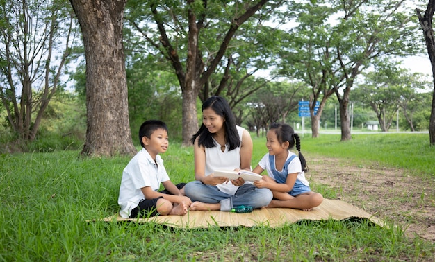 Famille asiatique, mère, fils et fille faisant des activités de lecture au parc