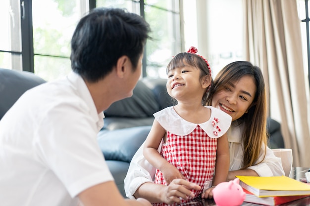 Une famille asiatique met de l'argent dans sa tirelire pour épargner