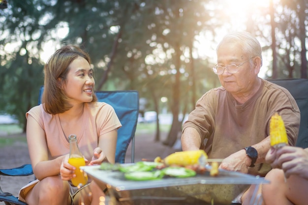 Famille asiatique avec personnes âgées buvant et faisant un barbecue ensemble. Cuisiner un barbecue grillé pour le dîner pendant le camping le doliday d'été.