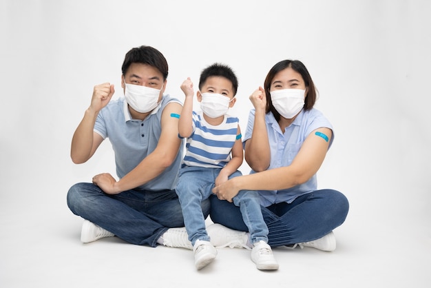 Famille asiatique portant un masque et montrant le bras avec du plâtre isolé sur fond blanc