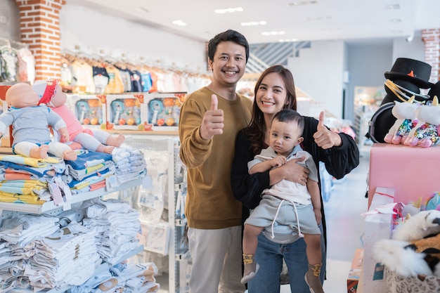 Famille asiatique avec son petit garçon faisant du shopping dans la boutique pour bébés avec le pouce vers le haut