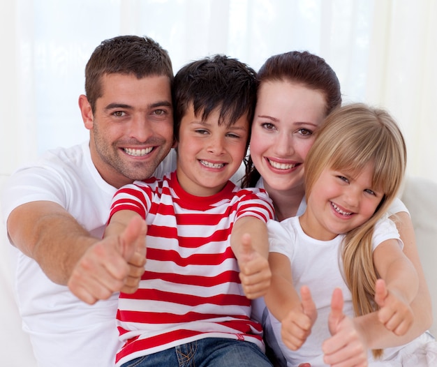 Famille assis sur le canapé avec les pouces vers le haut