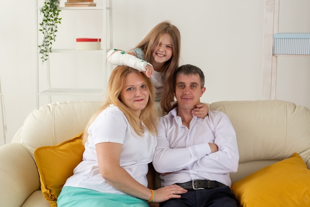 Photo une famille assise sur un canapé dans son salon a une blessure à la main mais elle est heureuse d'être ensemble