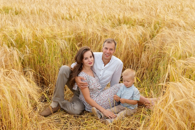 Famille assise sur l'herbe dans un champ de blé