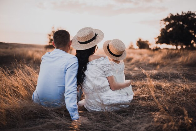 Famille assise sur l'herbe sèche dans la nature