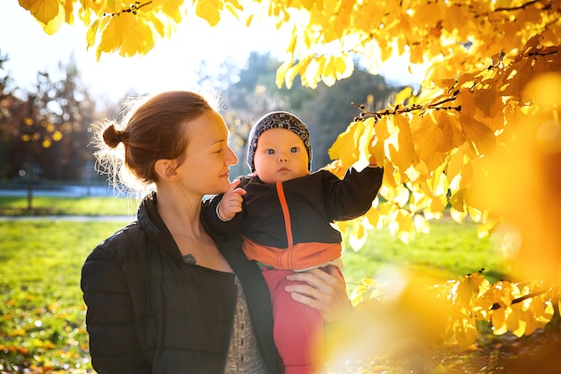 Photo famille en automne parc nature mère et bébé enfant heureux ensemble sur la nature à l'automne