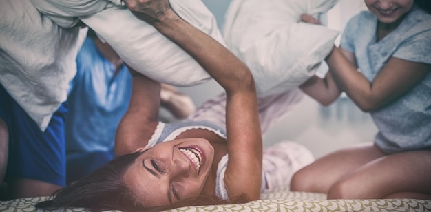 Famille ayant une bataille d'oreillers dans la chambre