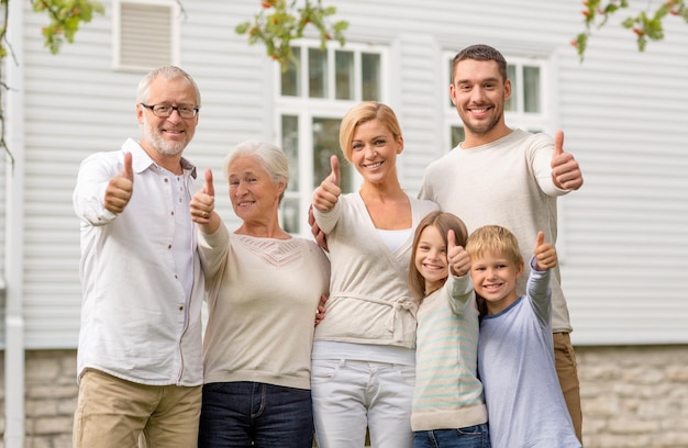 famille, bonheur, génération, maison et concept de personnes - famille heureuse debout devant la maison à l'extérieur