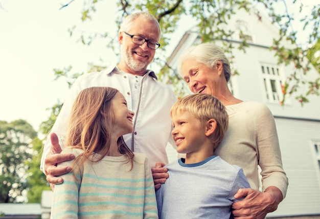 famille, bonheur, génération, maison et concept de personnes - famille heureuse debout devant la maison à l'extérieur