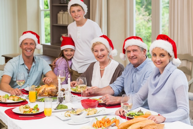 Famille en bonnet de Noel en regardant la caméra à Noël