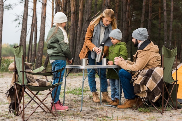 famille buvant du thé chaud à l'extérieur lors d'une randonnée d'automne