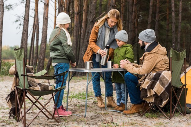 famille buvant du thé chaud à l'extérieur lors d'une randonnée d'automne