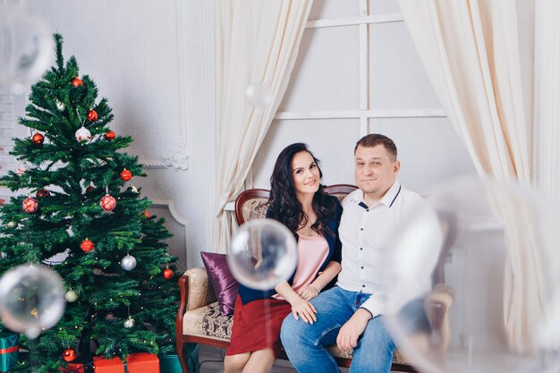 Famille avec un cadeau à l'arbre de Noël. la femme, l'homme et l'enfant sont assis sur le canapé.