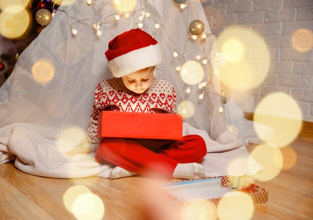 Famille avec des cadeaux à la veille de Noël garçon drôle allongé sur le sol avec un cadeau