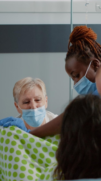 Une famille caucasienne en travail d'accouchement reçoit une assistance médicale dans un lit d'hôpital. Docteur en obstétrique et infirmière afro-américaine aidant une femme enceinte à pousser pour l'accouchement