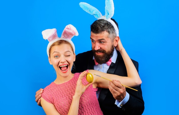 La famille célèbre Pâques et peint l'oeuf. Couple en oreilles de lapin avec oeuf de Pâques.