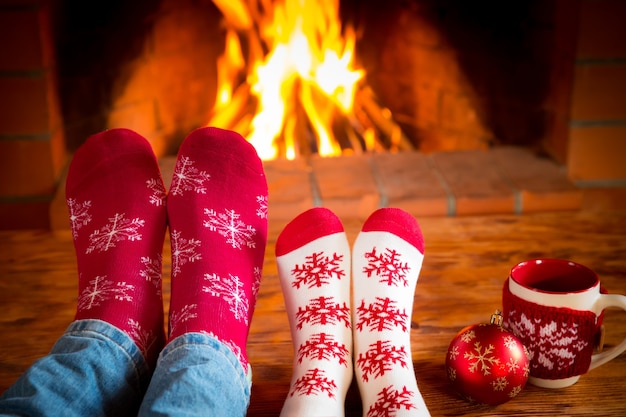 Famille en chaussettes de Noël près de la cheminée. Mère; père et bébé s'amusant ensemble. Les gens se détendent à la maison