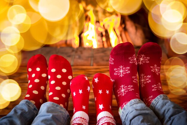 Famille en chaussettes de Noël près de la cheminée