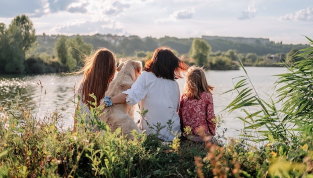 Famille avec chien golden retriever assis à l'extérieur dans la nature