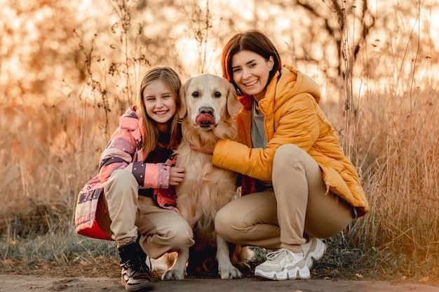 Famille avec chien golden retriever avec coucher de soleil à l'extérieur Mère fille et fille enfant avec chien labrador animal à la nature à l'automne