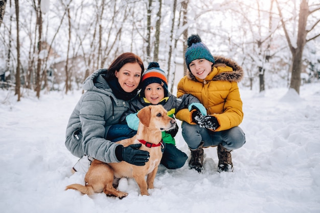 Famille avec chien jouant dans la neige