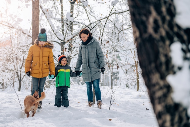 Famille avec chien marchant sur une neige fraîche