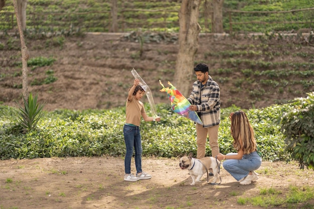 Famille avec un chien préparant un cerf-volant pour voler dans un parc