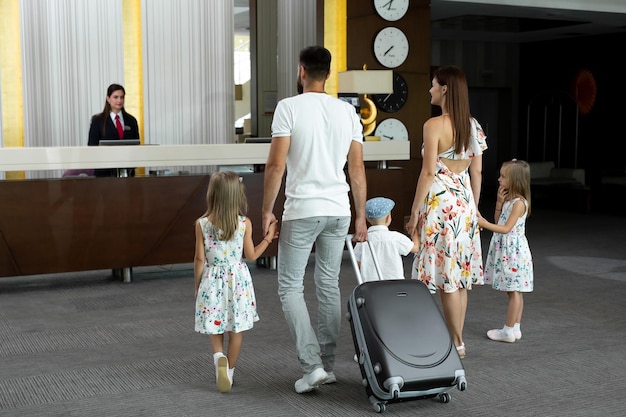 Une famille de cinq personnes entre dans le hall de l'hôtel pour s'enregistrer à la réception pour les vacances