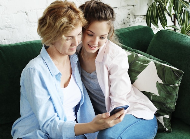 Famille et concept technologique Femme âgée et sa fille adulte utilisant un smartphone à la maison