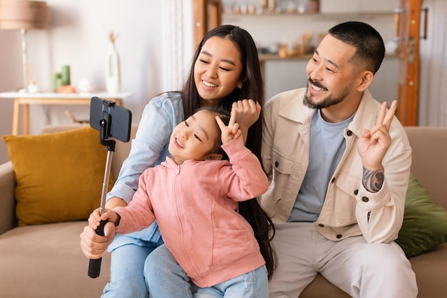 Famille coréenne faisant selfie sur smartphone posant ensemble à la maison