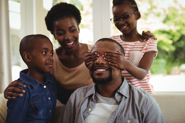 Famille couvrant les yeux de l'homme pour la surprise