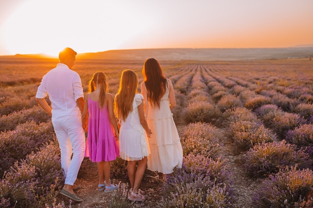 Famille dans le champ de fleurs de lavande au coucher du soleil en robe blanche et chapeau