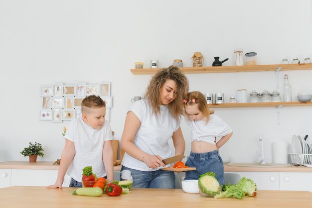 Famille dans une cuisine. Belle mère avec enfants. Dame en chemisier blanc.