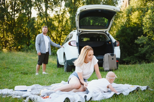 Famille dans une forêt. Les gens près de la voiture. Fond de coucher de soleil.