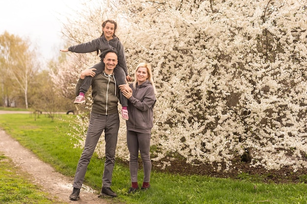 Famille dans un jardin fleuri avec des arbres.