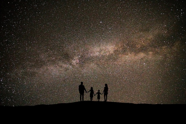 La famille debout sur le beau fond de ciel étoilé