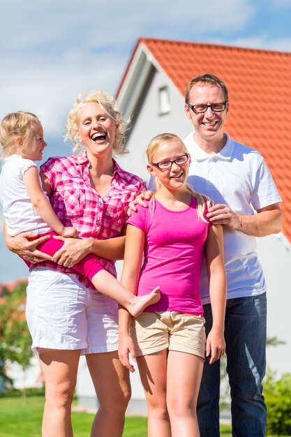 Famille debout fière devant la maison