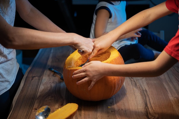 Famille découpant une citrouille d'halloween sur un bureau en bois