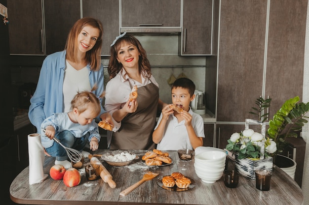 Famille : deux femmes et enfants préparent un gâteau d'anniversaire dans la cuisine.