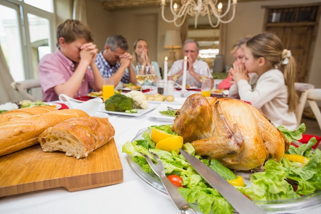 Famille disant la grâce avant le dîner de noël ensemble