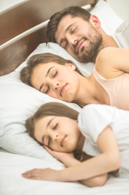 La famille dormant sur le lit confortable