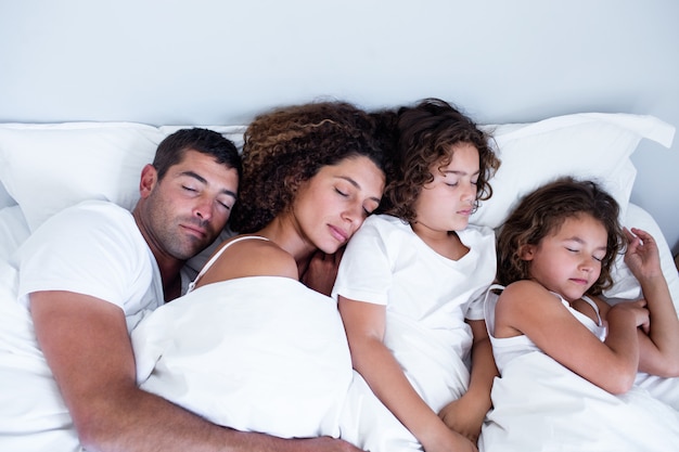 Famille dormir ensemble sur lit